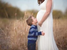 Menino bejando barriga de grávida de sua mãe